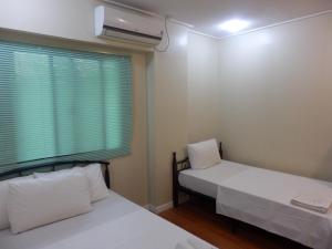 奥隆阿波Casa Saudade Condotels and Transient Rooms的小型客房 - 带2张床和窗户