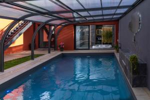 勒芒Villa Seyal - avec piscine - jacuzzi - sauna & climatisation的一座带凉亭和房屋的室内游泳池