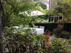 马斯特里赫特安妮列斯普雷斯住宿加早餐旅馆的花园配有两把白色椅子和遮阳伞