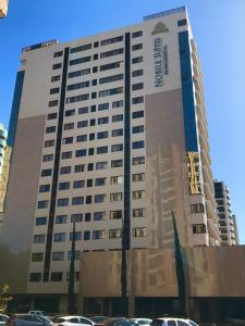 巴西利亚诺比尔纪念套房酒店的一座高大的建筑,旁边有一个标志