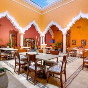 梅里达Viva Merida Hotel Boutique的餐厅拥有橙色的墙壁和桌椅