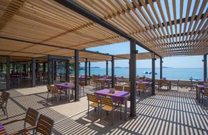 米利尼Maistra Select Mlini Hotel的一个带紫色桌椅的庭院和大海