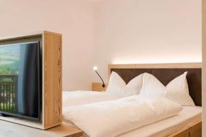 丘萨Natur Suite Edelweisshof App Ferdi的一张带白色枕头的床和一台电视机