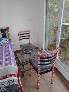 马尔舍吉加特Jandyal Farm House的一间设有两把椅子、一张桌子和一个窗户的房间