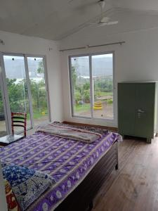 马尔舍吉加特Jandyal Farm House的一间卧室设有一张床和一个大窗户