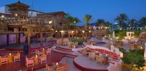 沙姆沙伊赫Private Luxury Villas at Sharm Dreams Resort的夜间带桌椅的户外庭院