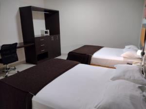 皮乌拉Intiotel Piura的一间卧室配有两张床、一张桌子和一面镜子