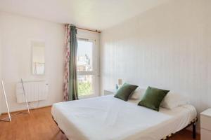 拉库尔讷夫Appartement à 10 minutes du centre de Paris avec le RER B的卧室配有带绿色枕头的大型白色床