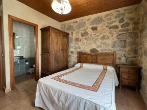 阿维拉Casa La Colmena Ávila的一间卧室设有一张床和石墙