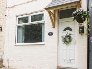 切斯特菲尔德Appletree Cottage的房屋的白色门,上面有花圈