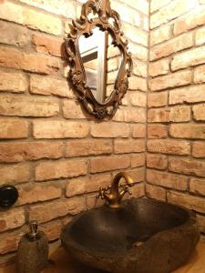特拉凯Pirties namelis ant ežero kranto的浴室的盥洗盆与砖墙上的镜子