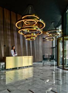 华沙Mennica Residence Luxury Location的站在大厅里带吊灯的柜台上的女人