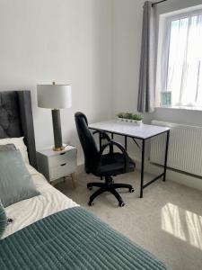 朴次茅斯Portsmouth City Centre Modern Apartment - with Free Parking的一间卧室配有书桌、椅子和床