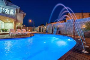 雷乌斯Villa Luxury Rock Tirri的后院的游泳池,在晚上设有喷泉