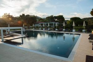 阿祖罗港Resort Capo Bianco的一个带椅子和遮阳伞的大型游泳池