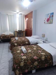 塔拉拉Hospedaje Petro Talara的酒店客房,配有三张带鲜花的床