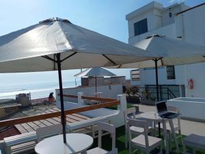 万查科Hospedaje Nuna - Playa Huanchaco的海滩上带桌子和遮阳伞的庭院