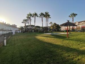 埃尔波提尔Adosado de lujo en El Portil Playa y Golf的一片种有棕榈树和遮阳伞的草地