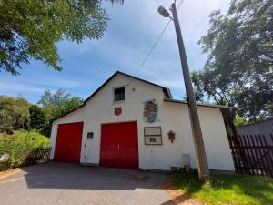 MittelndorfFerienhaus -Alte Feuerwehr- Mittelndorf的一座白色的小建筑,设有红色车库