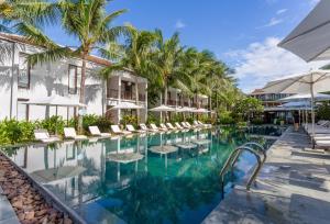 会安Emerald Hoi An Riverside Resort的度假酒店的游泳池配有椅子和遮阳伞