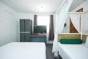 长滩岛8 Colors Beach House Resort的一间卧室配有两张床和电视。