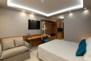 尼基季Lithos Suites - Nikiti Halkidiki的一间卧室配有一张床、一张沙发和一台电视。