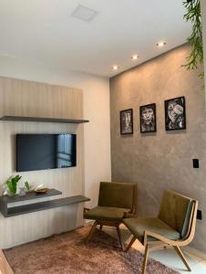 博阿维斯塔Condomínio tranquilo的客厅配有两把椅子和电视