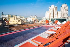马德里Akeah Hotel Gran Vía的一座带橙色椅子的建筑屋顶上的游泳池