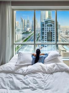 迪拜迪拜费尔蒙特酒店的躺在窗前床边的女人