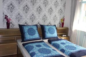 厄林根Ferienwohnung DaWie的一间卧室配有两张带蓝色枕头的床和墙壁