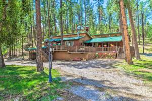 鲁伊多索Sleepy Bear Cabin in Ruidoso Deck and Yard Games!的树林中带门廊的大房子