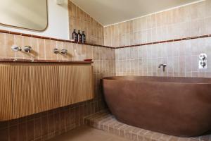 博尼约Capelongue, a Beaumier hotel & Spa的浴室设有棕色浴缸和镜子