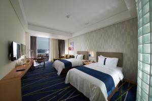 新郑郑州港区智选假日酒店的酒店客房设有两张床和电视。