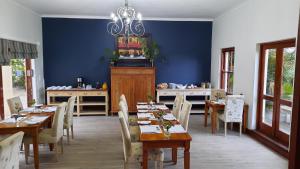 赫曼努斯薰衣草庄园旅馆的一间拥有蓝色墙壁和木桌及椅子的用餐室