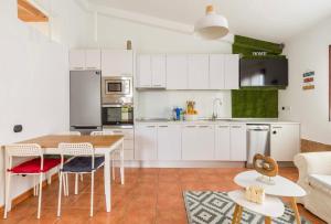 马斯帕洛马斯Fast wifi & Relax bungalow Ipanema Gran Canaria的厨房配有白色橱柜和桌椅