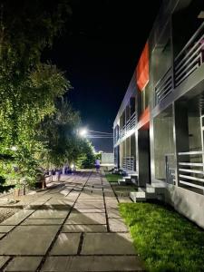 TamchyГостевой Комплекс ARTек的夜间在建筑物前的一条空的街道