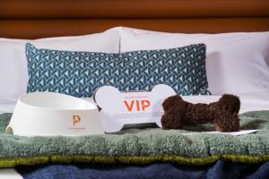 波特兰多西耶酒店的坐在杯子旁边的床上的泰迪熊