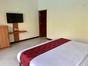 努沙杜瓦Davit Guesthouse Nusa Dua的一间卧室配有一张床和一台平面电视
