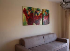 斯卡拉拉乔伊Xanthiotis Apartments的客厅配有沙发,墙上有三幅画作