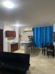 曼塔Playa Suites, cerca del Malecon的带沙发的客厅以及带蓝色窗帘的厨房