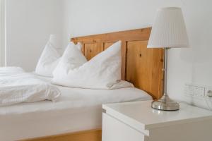 圣洛伦佐-迪塞巴托MANTANA - Apartments的白色的床、白色枕头和带台灯的桌子