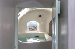 安坡里奥圣托里尼Exi Castle Suites的带浴缸和窗户的浴室