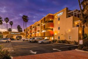 亨廷顿海滩Comfort Inn & Suites Huntington Beach的酒店门前设有停车场,可停放汽车