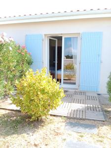 吉伦特河畔梅谢尔Chambre d'hôtes le Berceau的白色的房子,有蓝色的门和灌木
