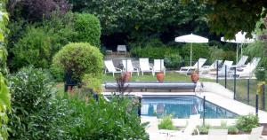 博让西Logis Hôtel La Tonnellerie的花园内带椅子和遮阳伞的游泳池