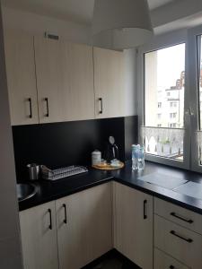 马尔堡Apartament Przy Ratuszu的厨房配有白色橱柜和黑色台面