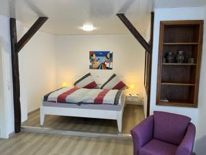 埃迪格尔-埃莱尔Haus Osterlämmchen的一间卧室配有一张床和一张紫色椅子