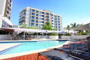 黄金海岸特色海滨公寓酒店的一座带椅子和遮阳伞的游泳池位于一座建筑旁边
