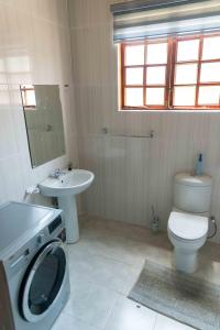卢萨卡Luxurious Chimwemwe II - Kat-Onga Apartments的浴室配有卫生间、盥洗盆和洗衣机。