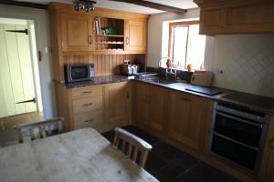 RaglanMedieval Cottage in rural Monmouthshire.的厨房配有木制橱柜、桌子和微波炉